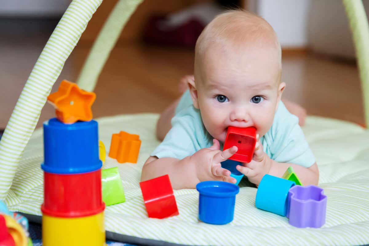 Bebé juega con cubos y mira algo fijamente.