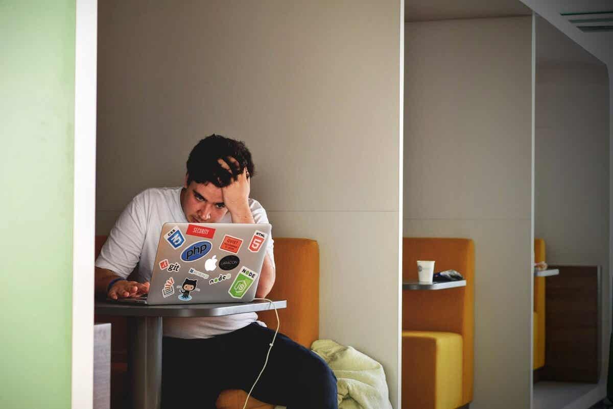 Chico con ordenador representando la depresión en estudiantes universitario.