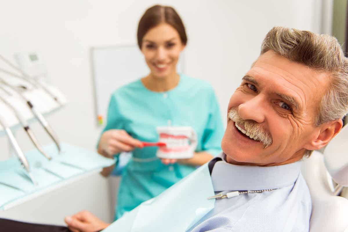 Hombre mayor en consulta con dentista por complicaciones de los implantes dentales.