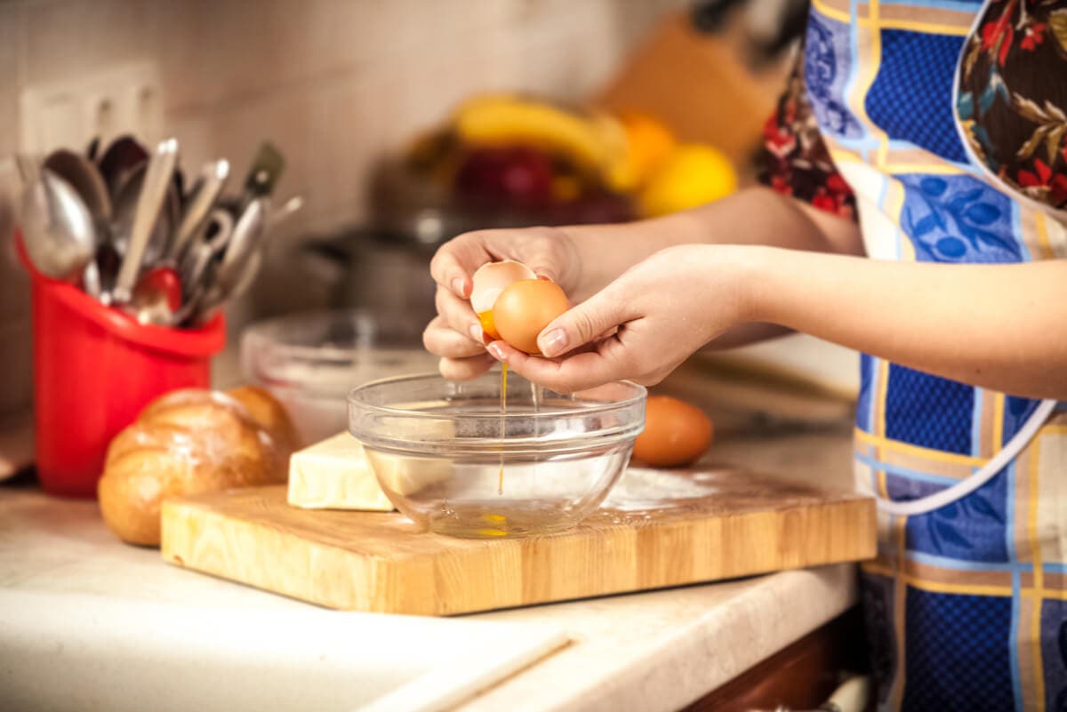 Femme qui casse un œuf.