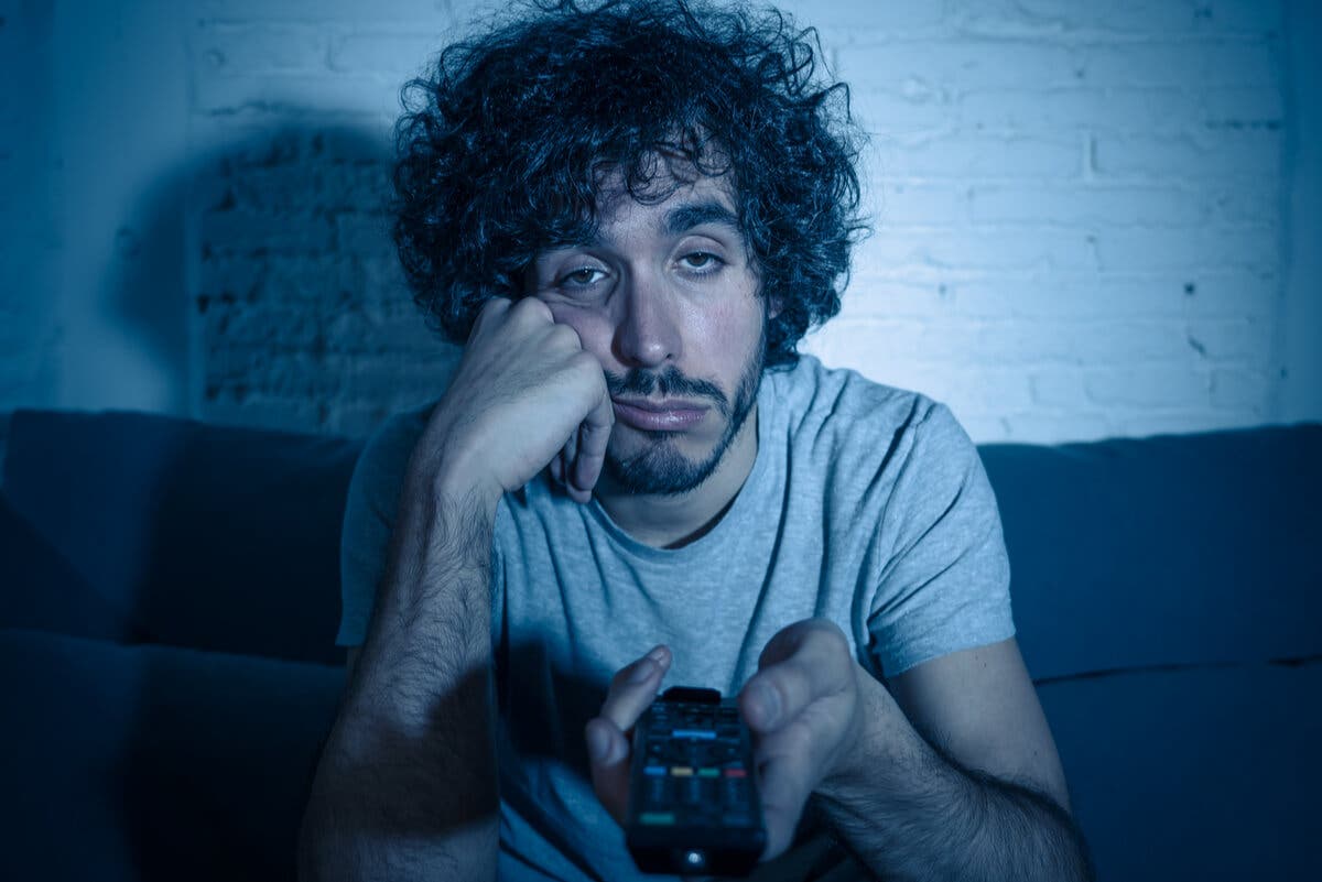 Hombre aburrido mirando televisión de noche.