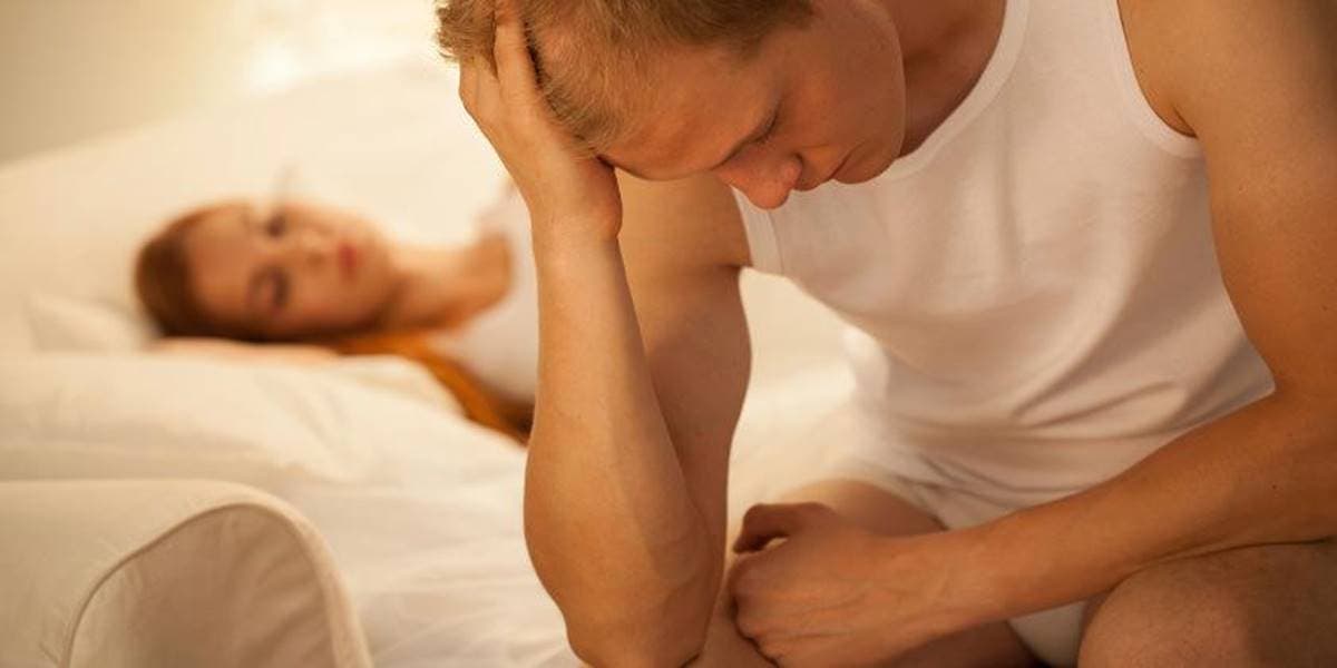 Hombre en la cama representando el estrés y la disfunción eréctil.