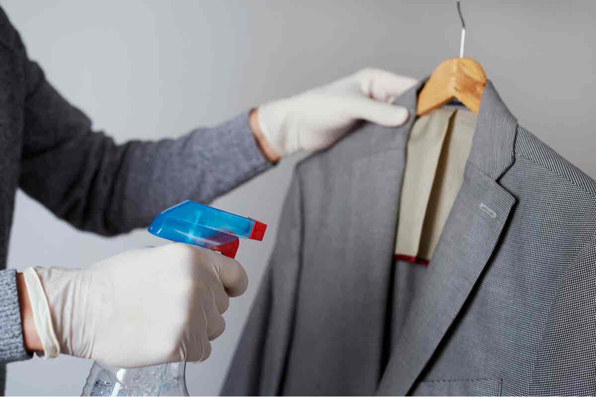 Falten aus Kleidung entfernen - Person sprüht Wasser auf eine Anzugjacke