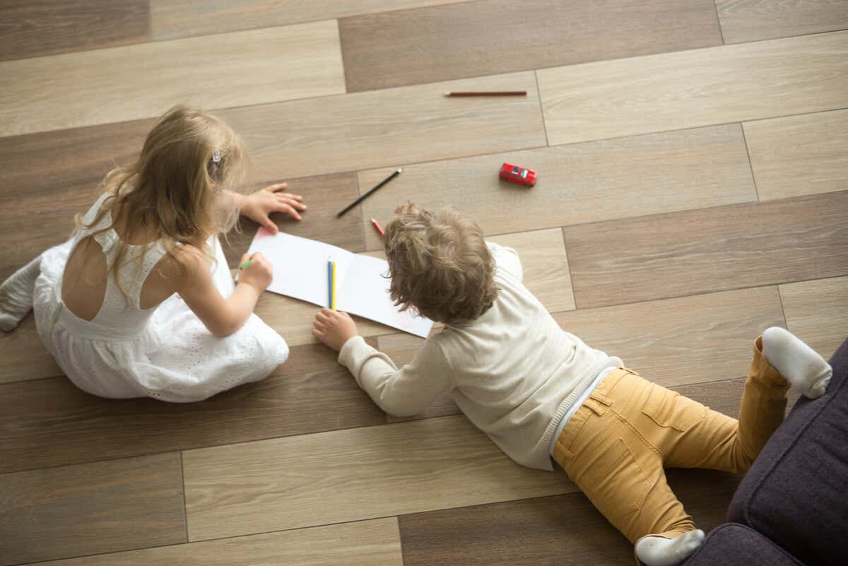 Niños rayan piso de madera.