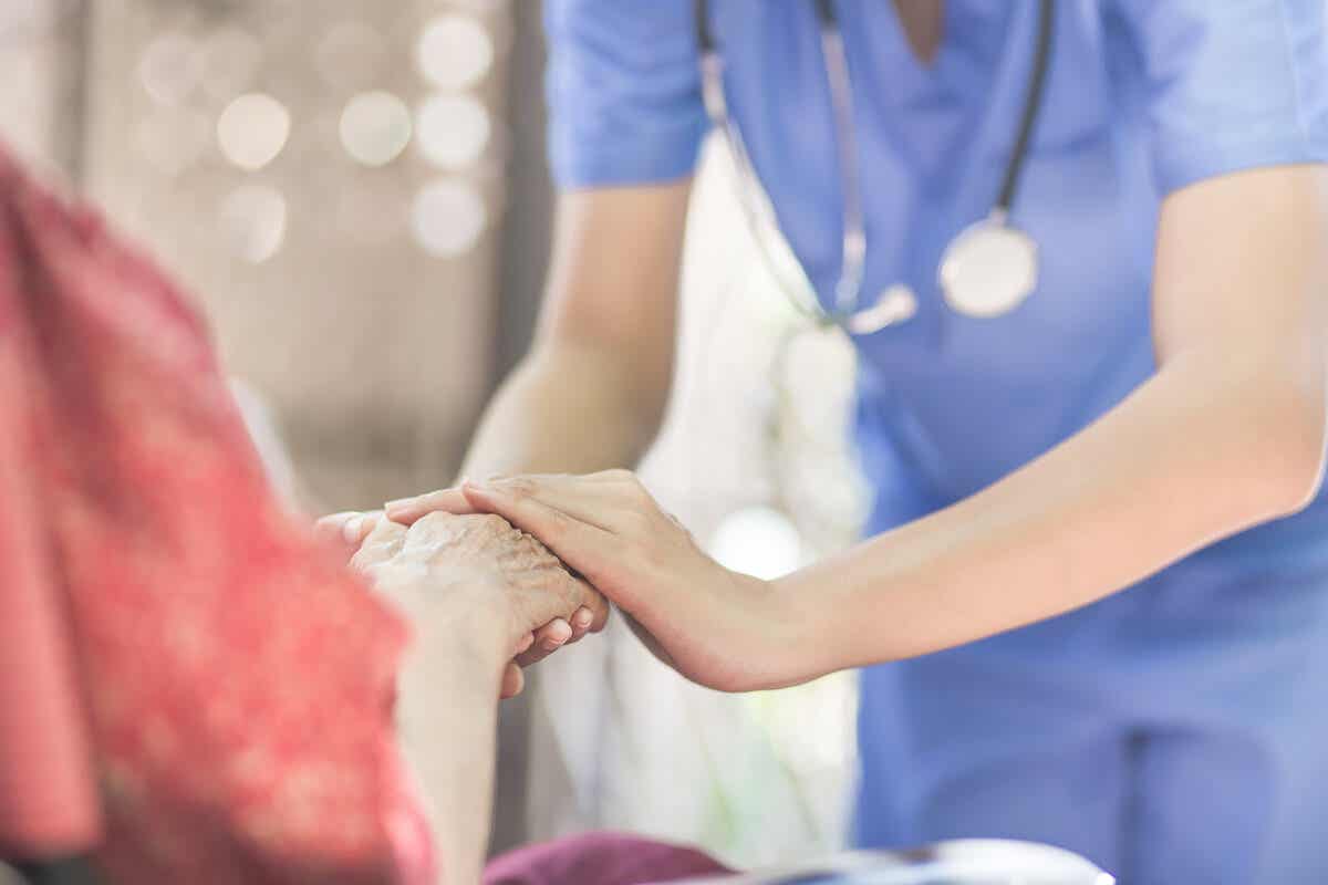 Verpleegster houdt de hand vast van een oudere vrouw