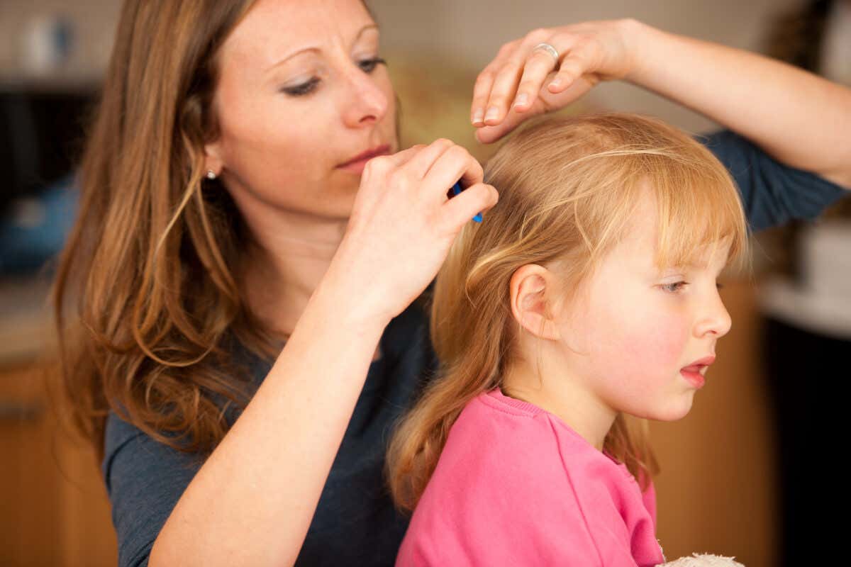En mor sjekker håret til barnet sitt.