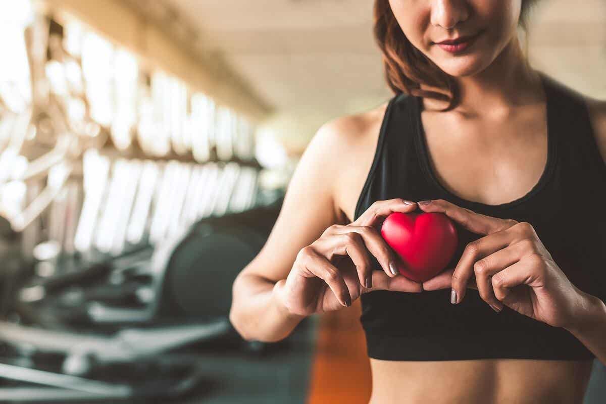Exktopischer Herzschlag - Frau im Fitnessstudio hält ein Herz in der Hand