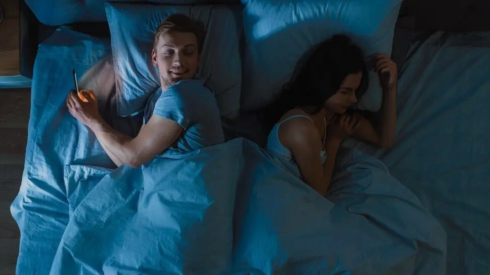 Homem praticando infidelidade virtual na cama