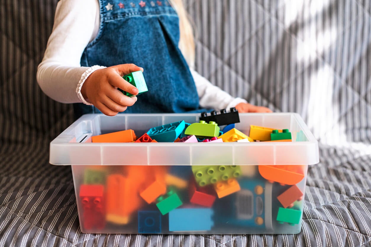 Spielzeugrotation - Kind vor einer Kiste Legosteine