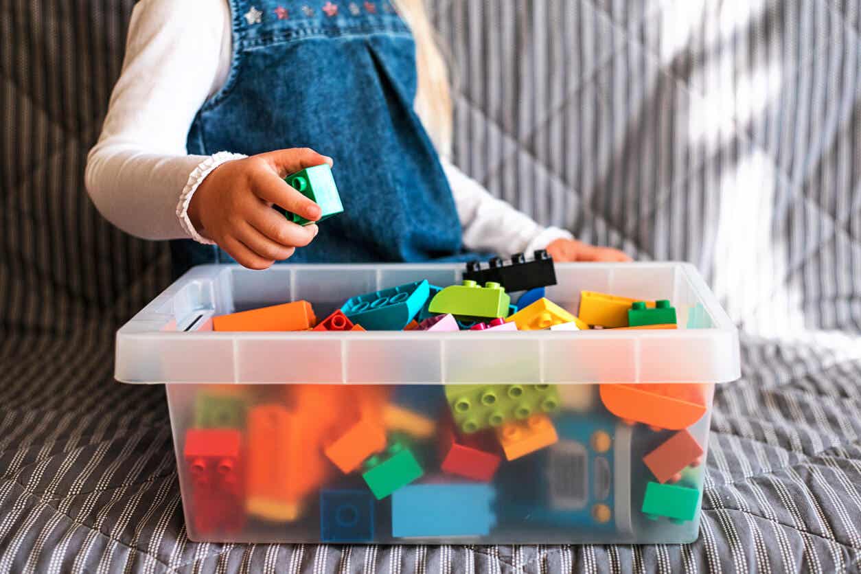 Spielzeugrotation - Kind vor einer Kiste Legosteine