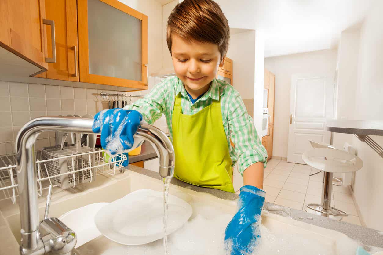 Niño lava los platos con autonomía e independencia.