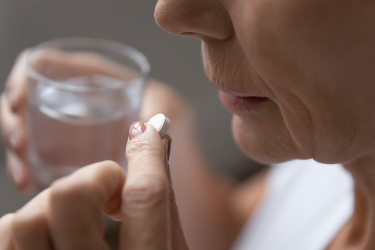 Tägliche Aspirin-Therapie - Frau nimmt eine Tablette ein