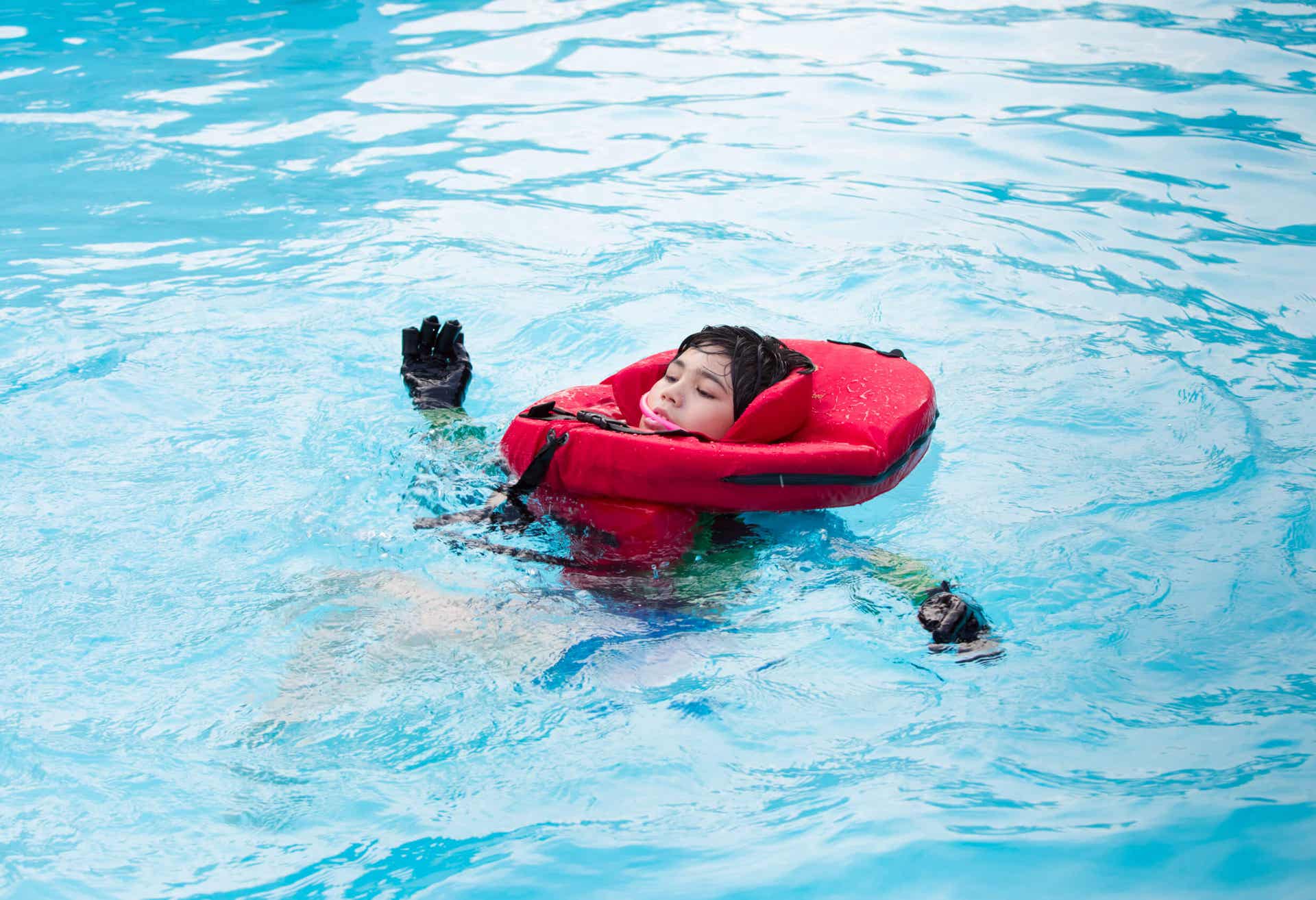 Mobilitätseinschränkungen - Kind schwimmt mit einem speziellen Schwimmring