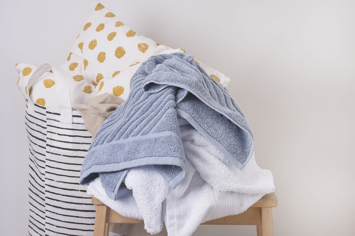 Natte handdoeken in de wasmand proppen