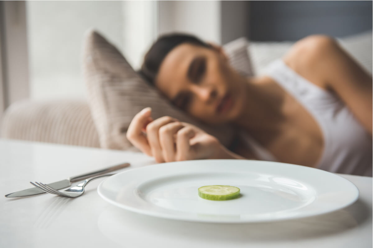 Bulimie und Magersucht - Frau neben einem Teller mit einer Scheibe Gurke