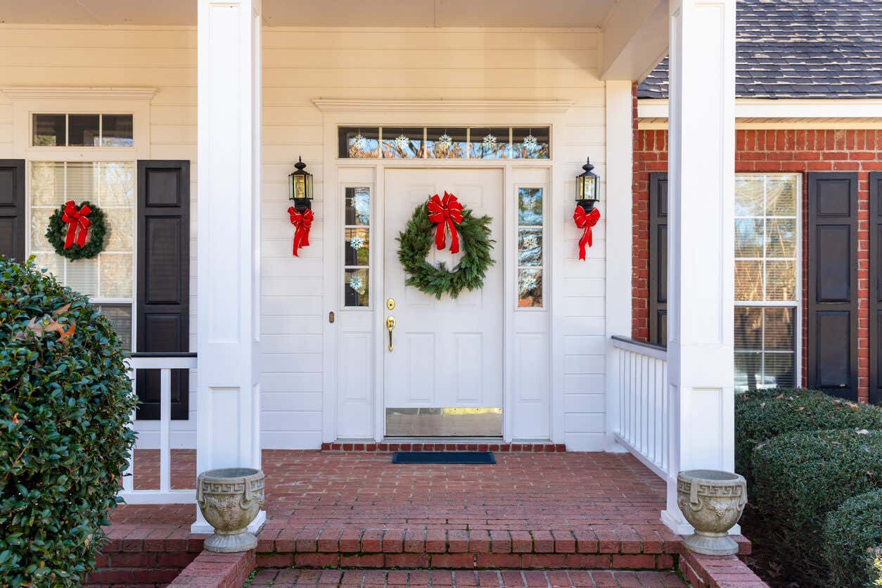 Entrada de un hogar decorado para navidad con guirnaldas y moños.