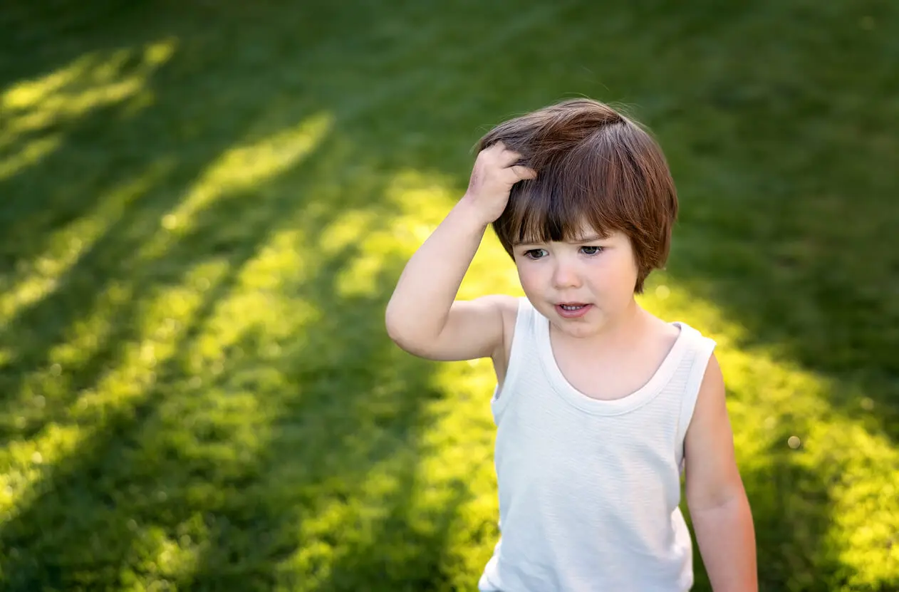 Niño rasca cabeza por tener piojos.