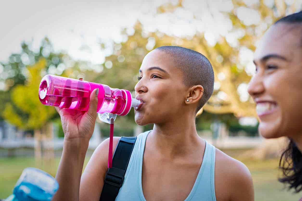 Kobieta pije wodę z butelki wielokrotnego użytku