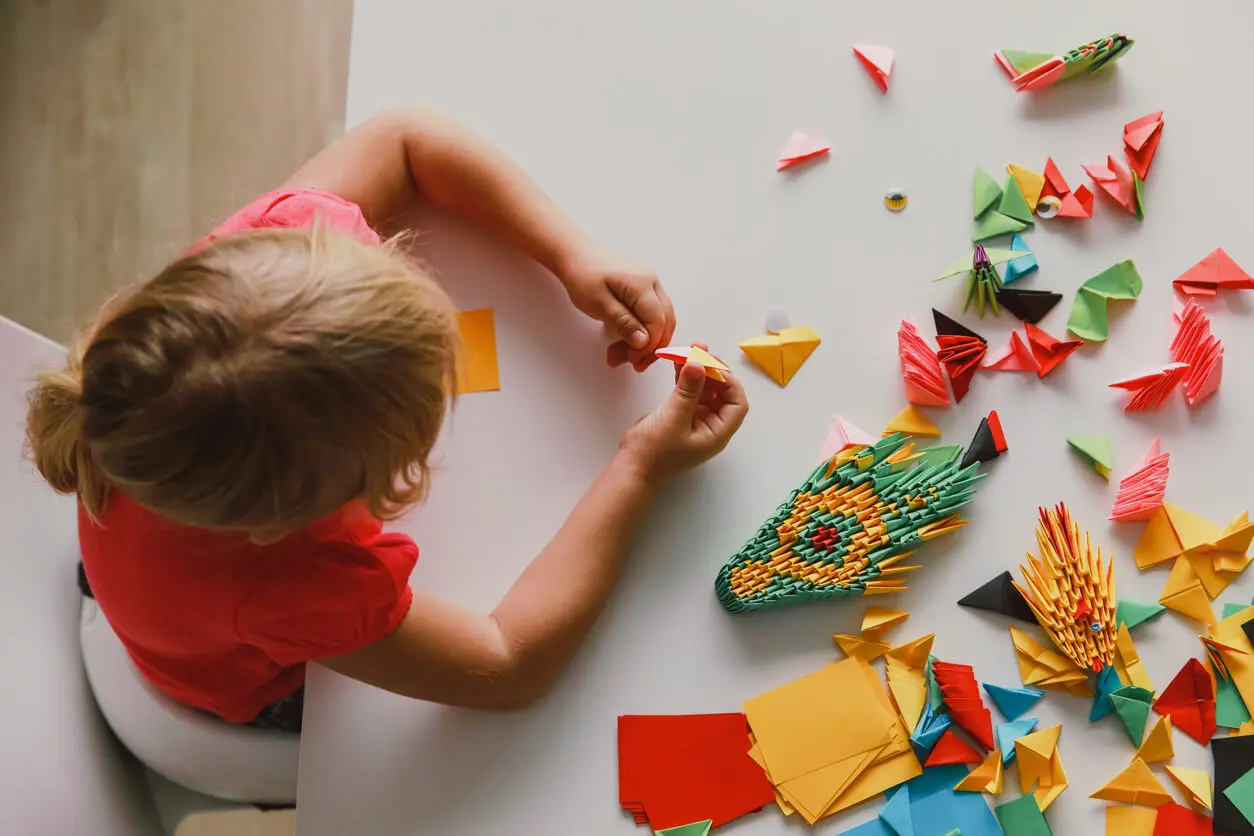 Les enfants font des origamis pour décorer une fenêtre sans rideaux.