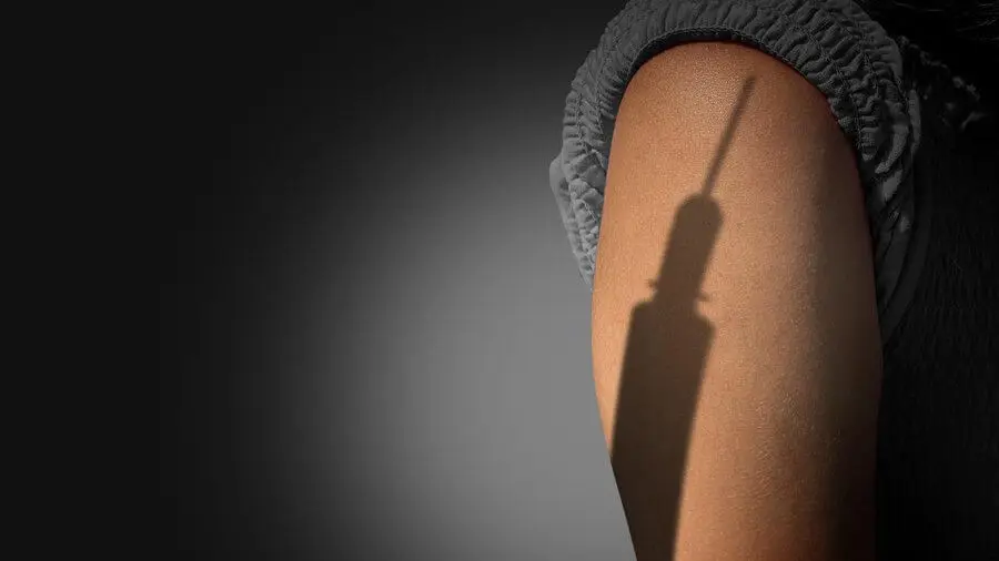 Sombra de una inyección en una persona con miedo.