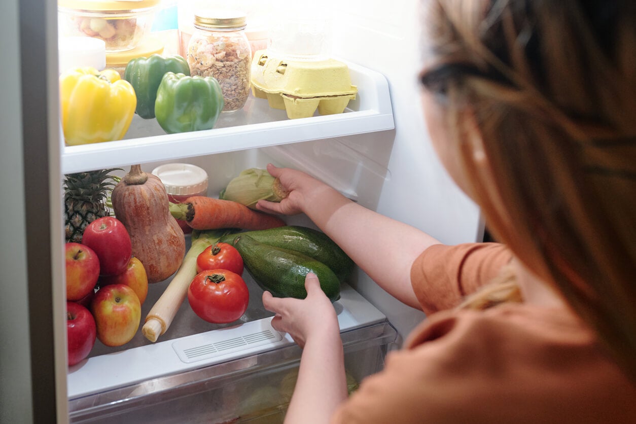 Mujer buscando verduras en el congelador.