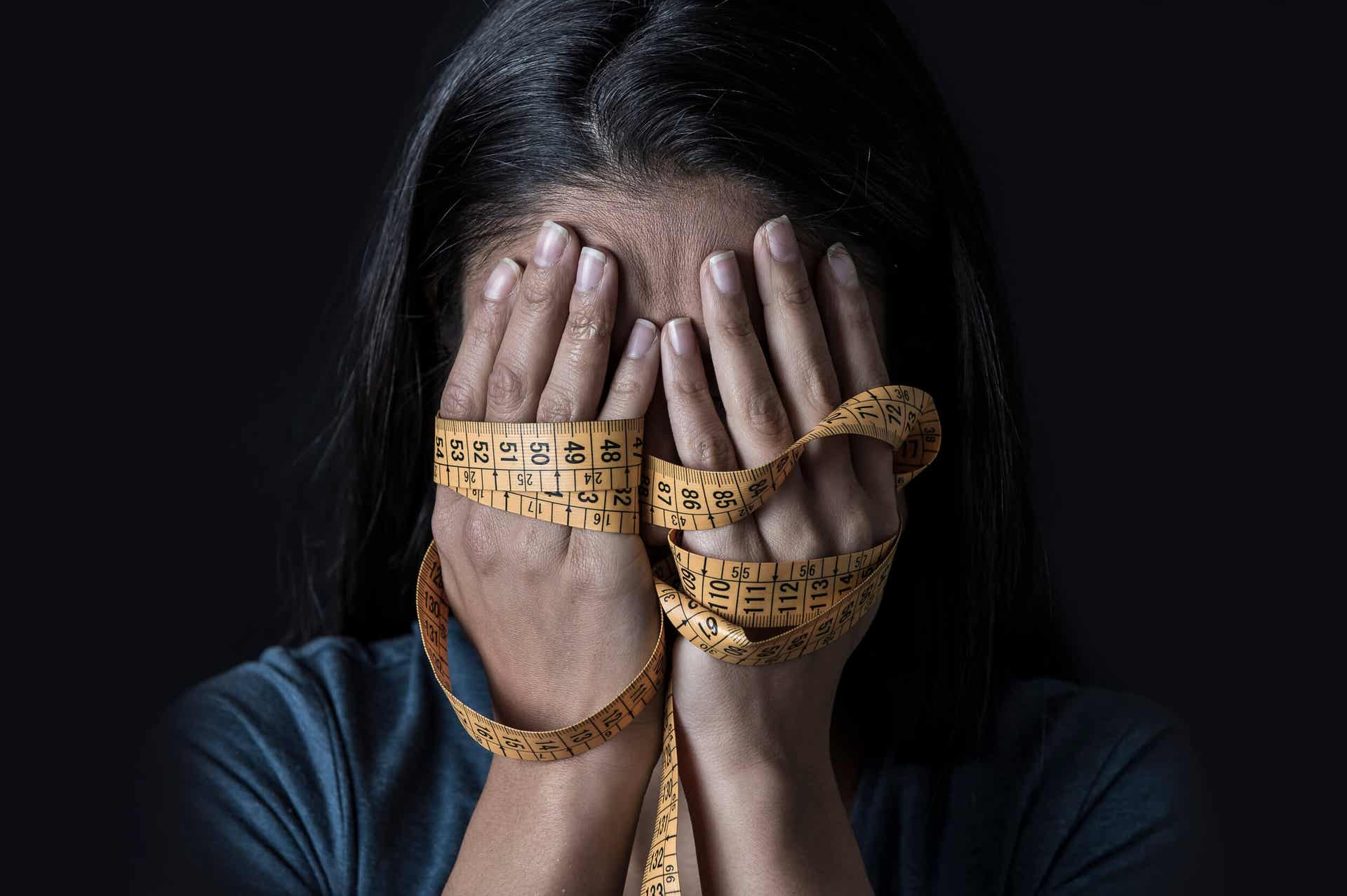 Bulimie und Magersucht - Frau mit einem Maßband in der Hand