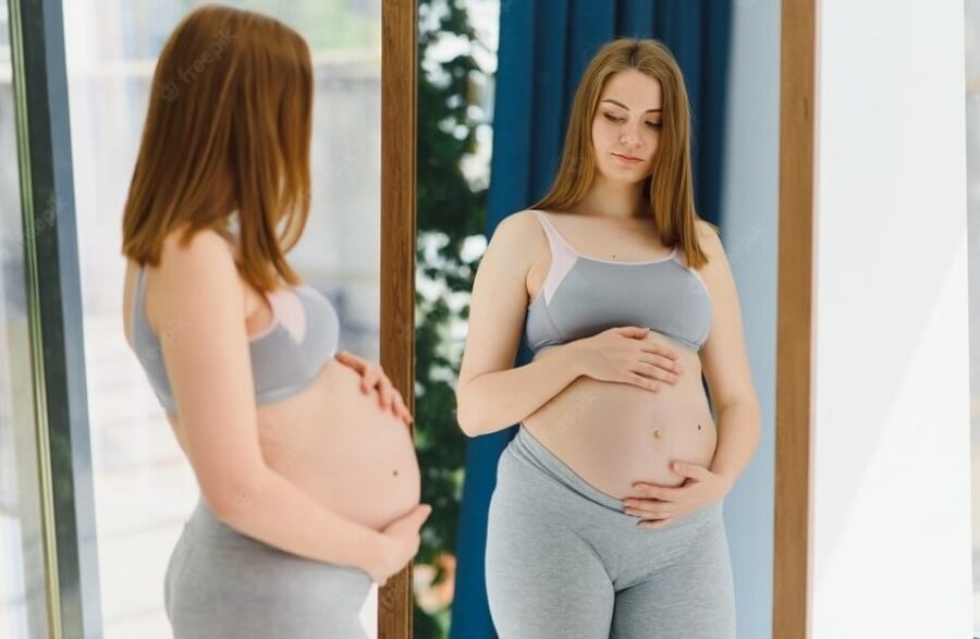 Mujer embarazada frente al espejo.