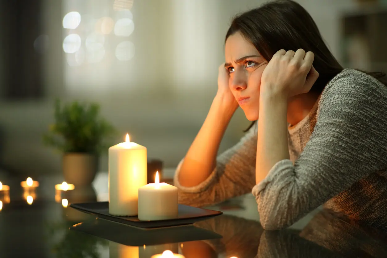 Mujer enfadada enciende velas en un apagón.