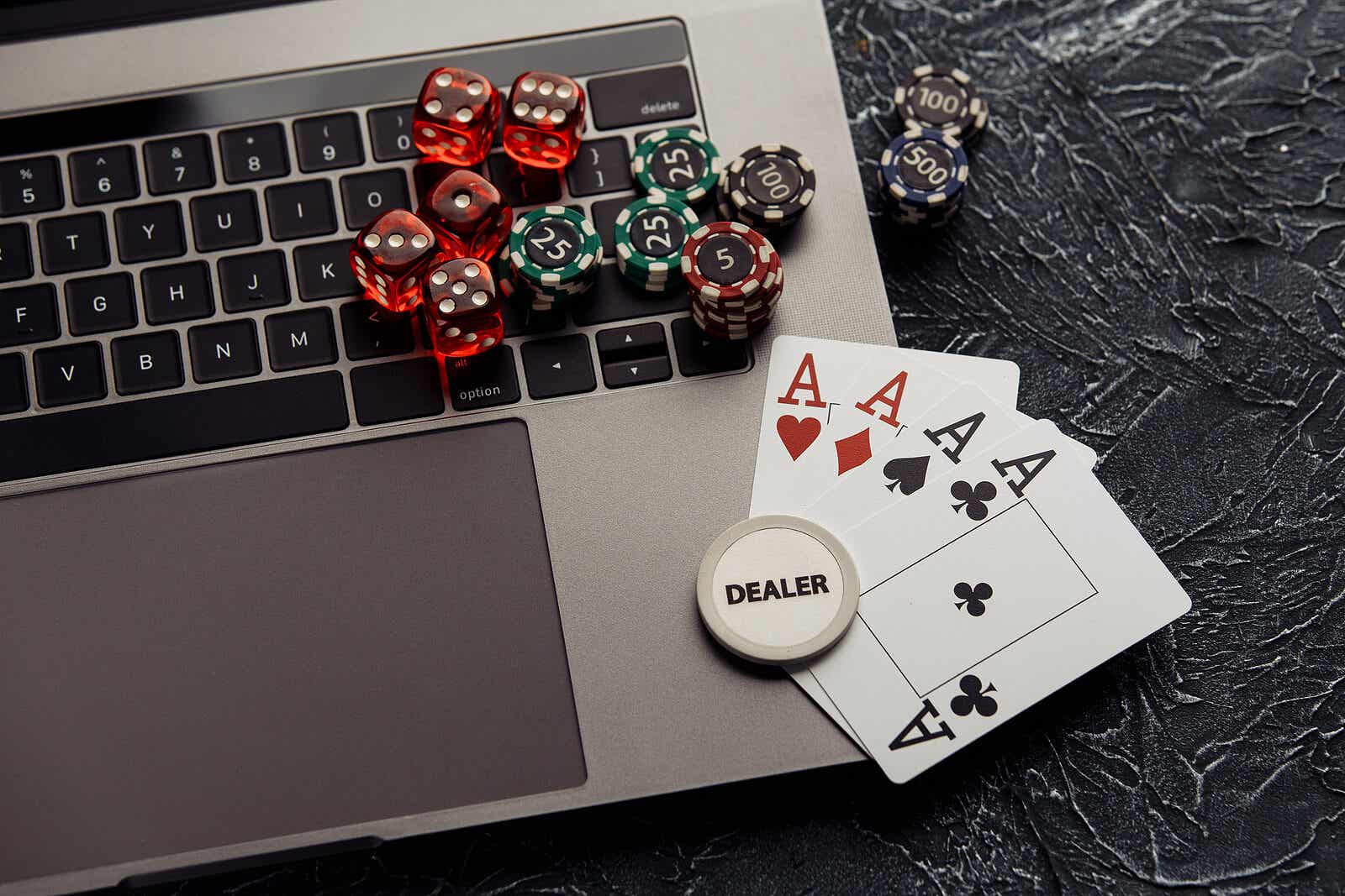 Cyber-Glücksspielsucht - Spielkarten und Würfel auf einem Laptop