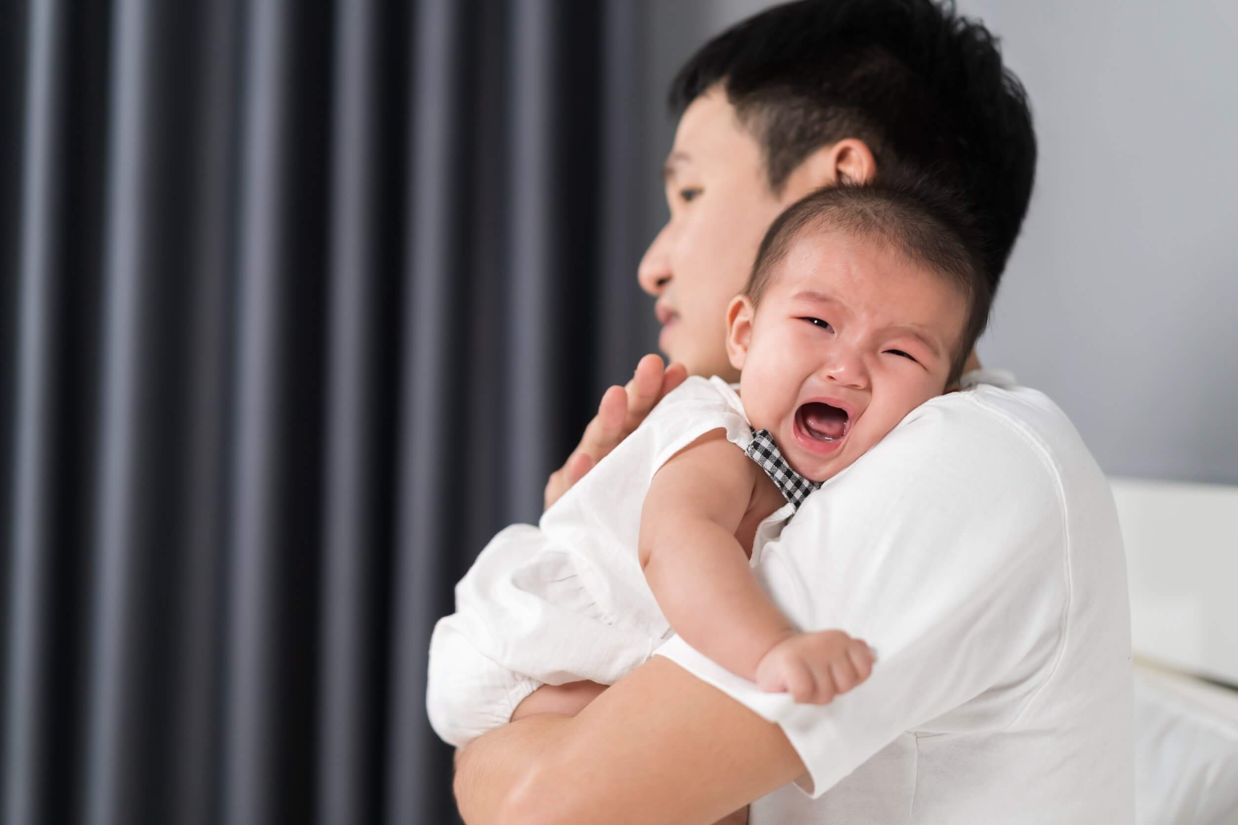 Padre con bebé llorando.