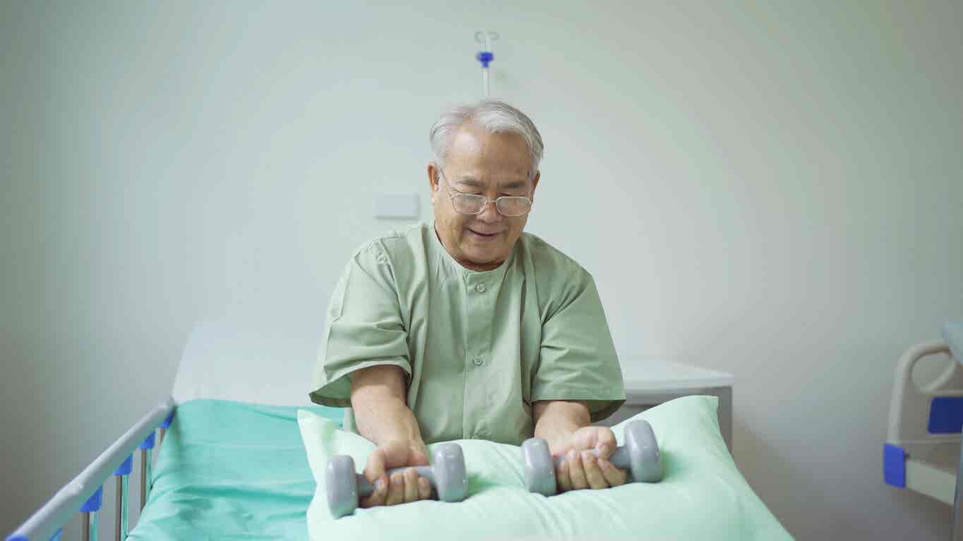 Un homme âgé fait des exercices au lit.