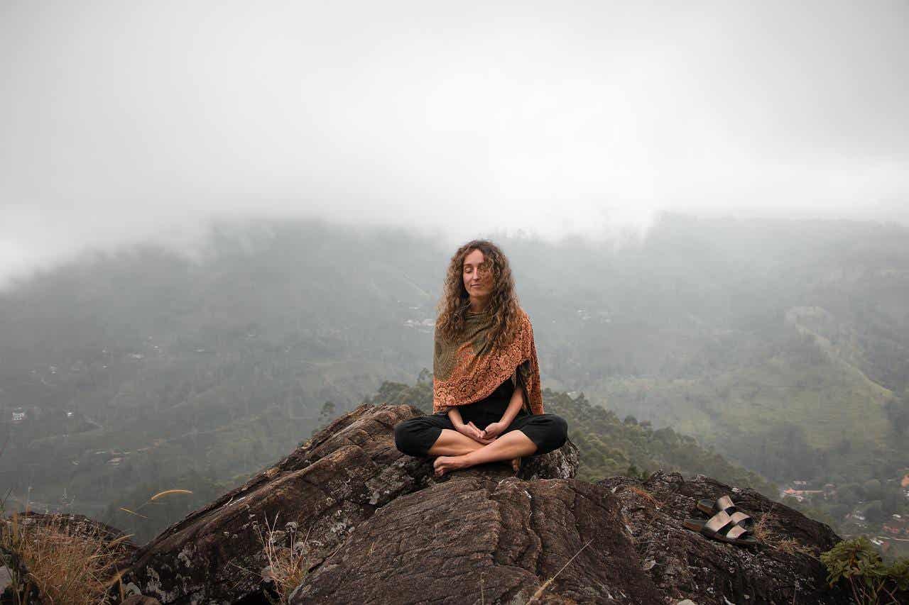 Reflektierender Mensch - Frau meditiert auf einem Berg