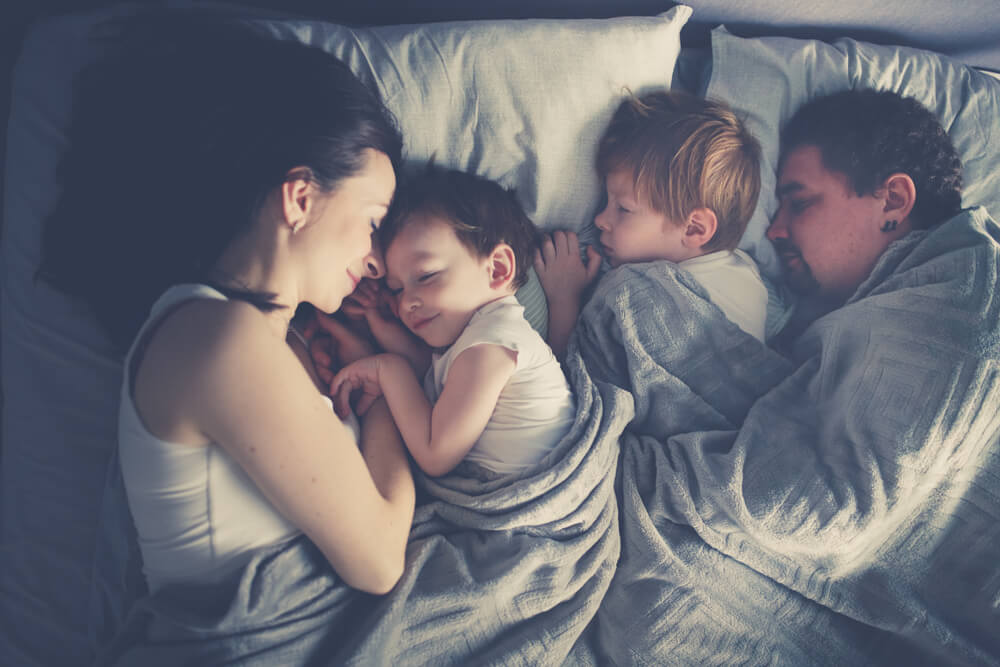 Enfants dormant avec leurs parents.