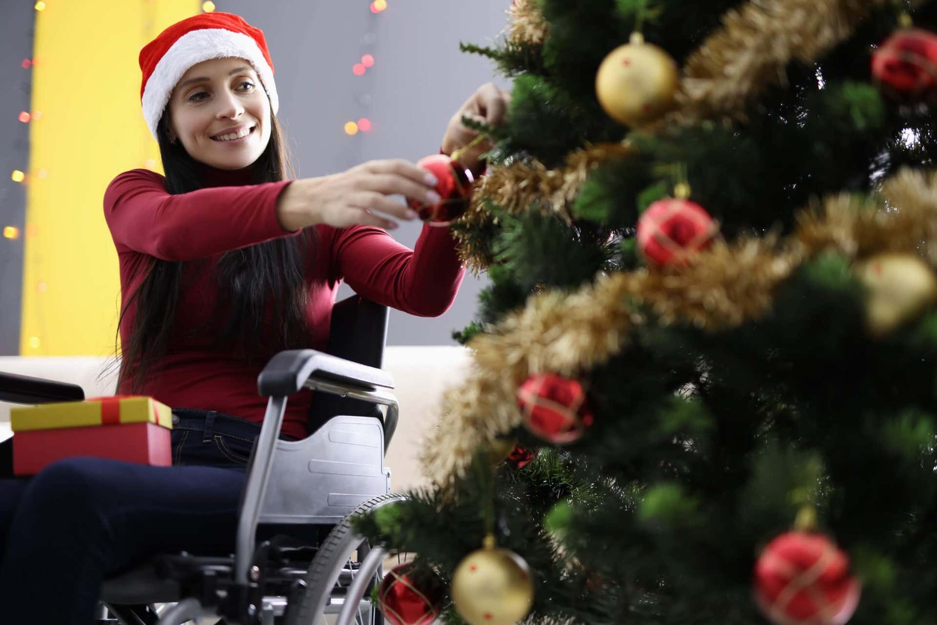 Kvinde i kørestol pynter juletræ og repræsenterer en inkluderende jul