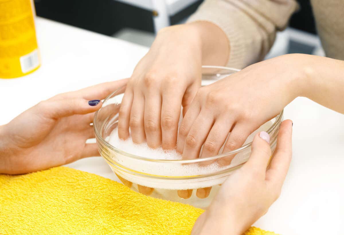Remojar manos en agua con jabón.