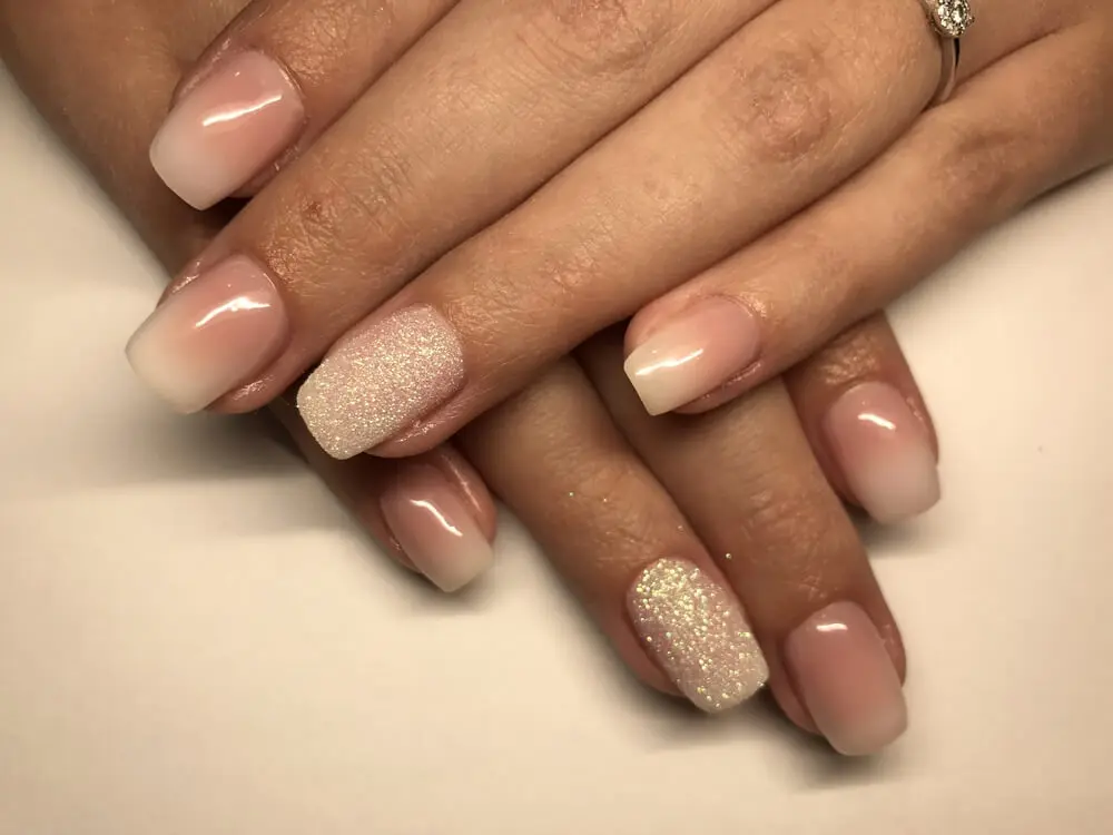 Diseño de uñas baby boomer con glitter.