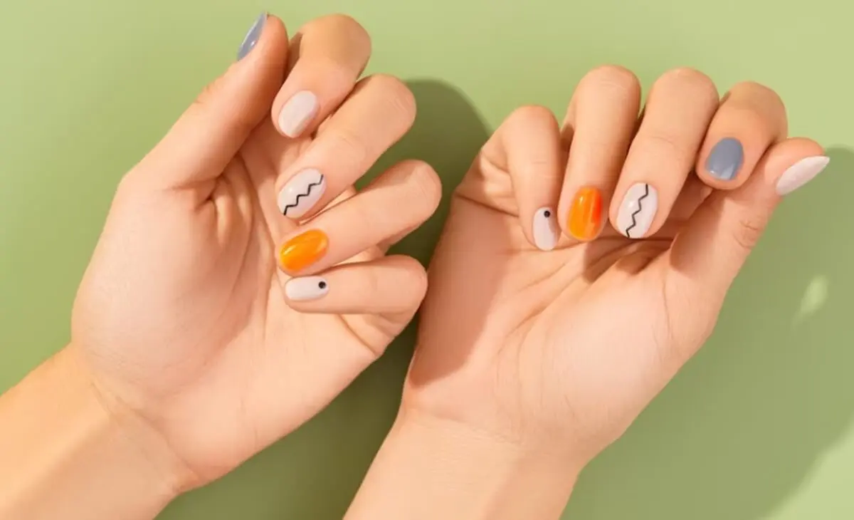 Uñas minimalistas en colores grises, naranja y blancos.