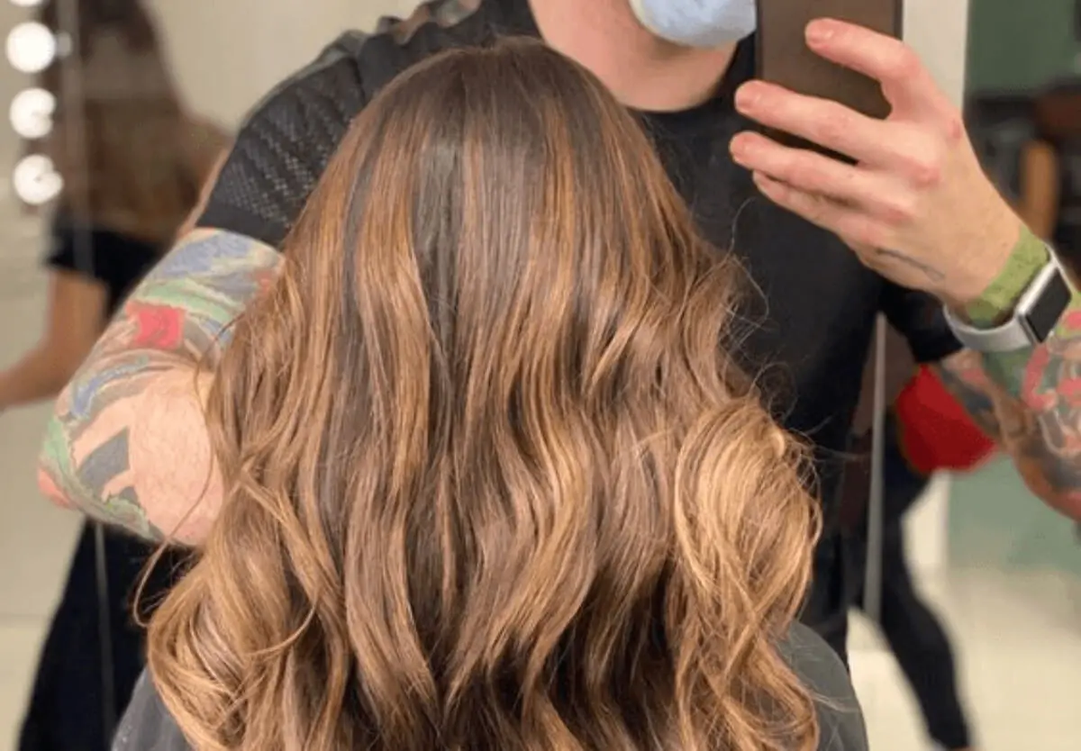 Mujer con cabello negro y tonos claros en la peluquería.