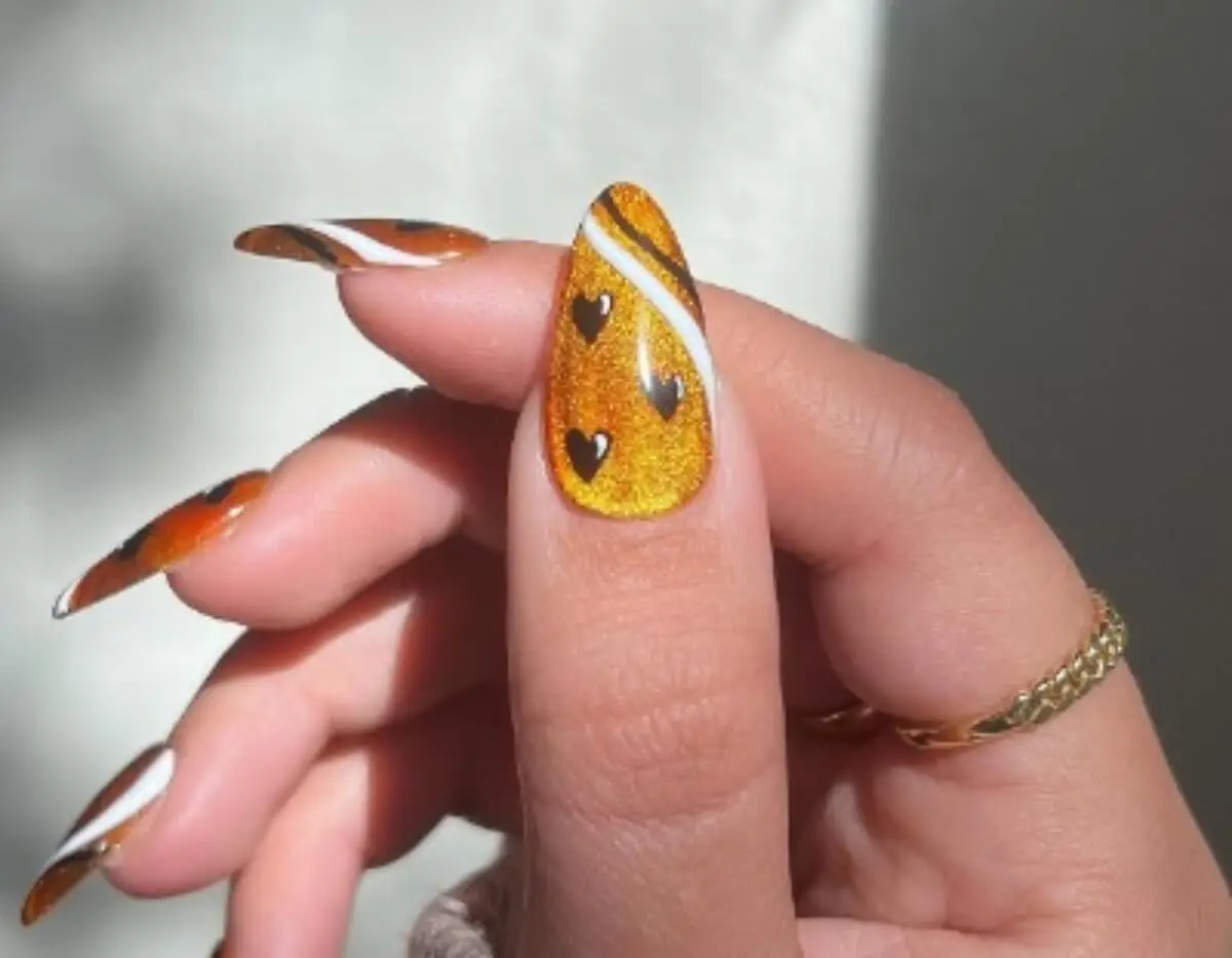 Velvet nails naranja con detalles en negro y blanco.