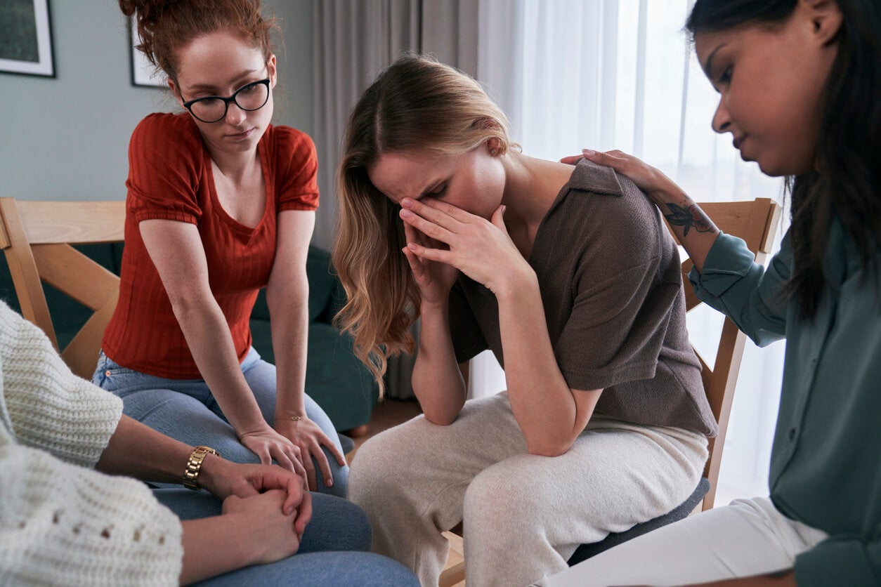 Mujer triste recibe apoyo de su círculo de amigas. Querer tener pocos amigos. 