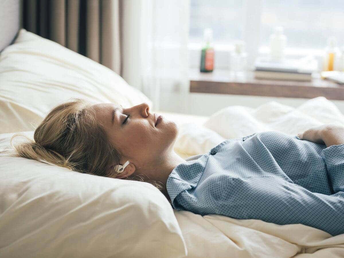 Mujer realiza respiraciones antes de descansar, en un ambiente adecuado para dormir.