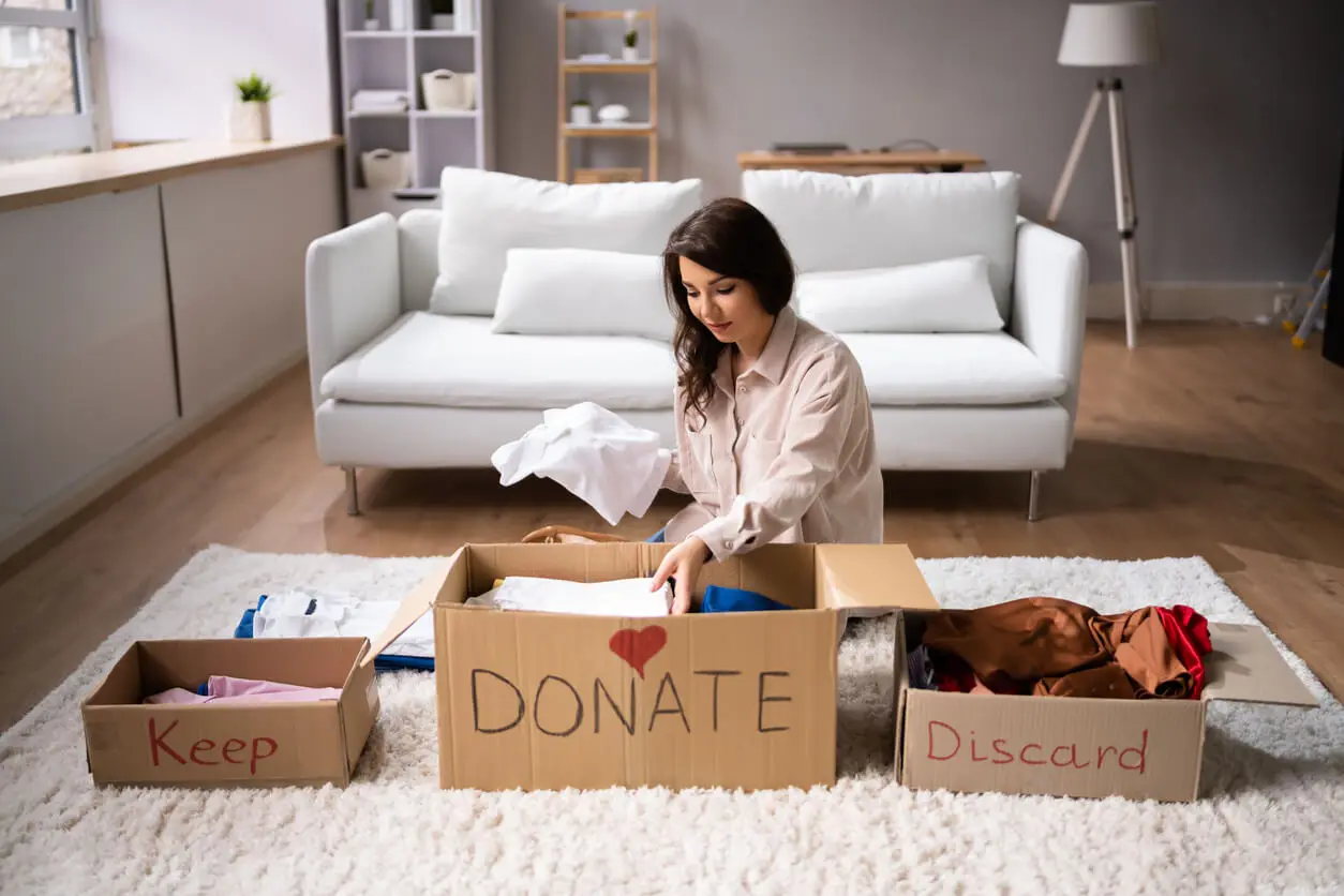 Mujer clasifica ropa para donación, quedarse y descartar.