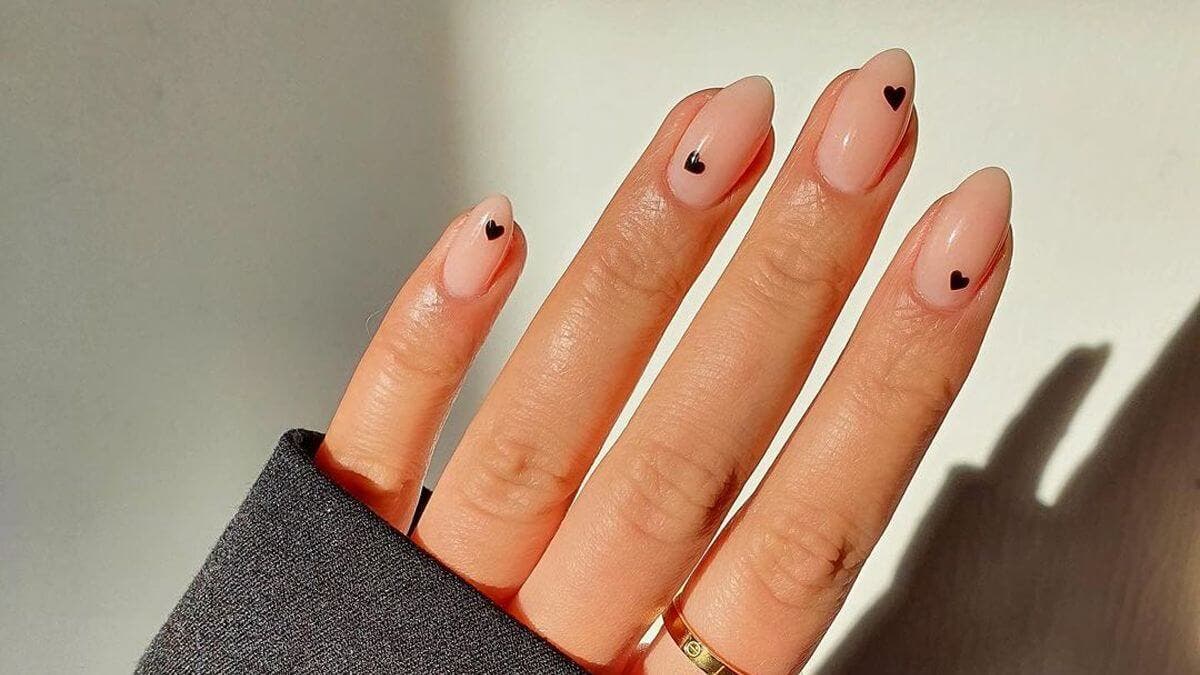 Uñas minimalistas con corazones negros.