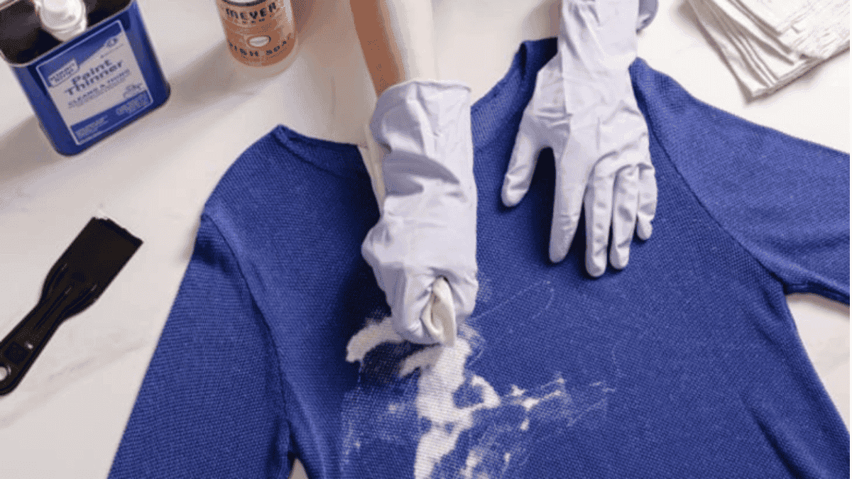 Persona frota mancha en camiseta. ¿Cómo quitar pintura de la ropa?
