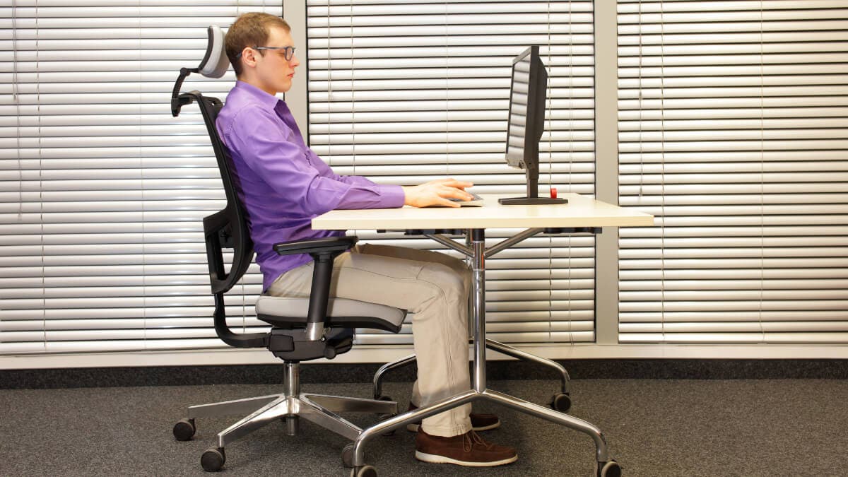 Hombre mantiene buena postura con ayuda de silla ergonómica.