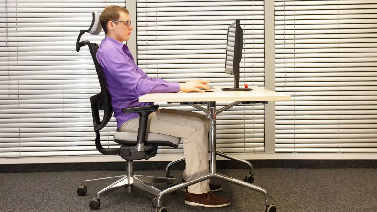 Hombre mantiene buena postura con ayuda de silla ergonómica.