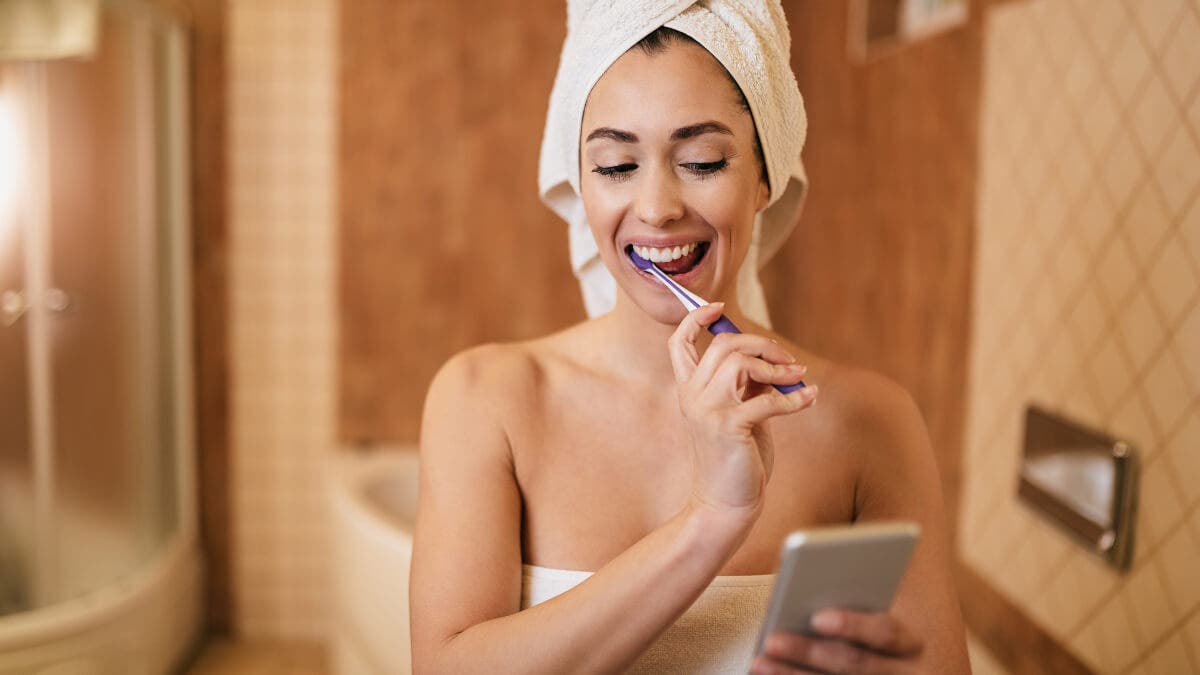 Une femme surveille la durée du brossage avec un chronomètre de téléphone portable