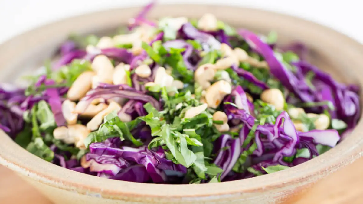 Ensalada de alubias blancas con col morada sobre plato hondo.