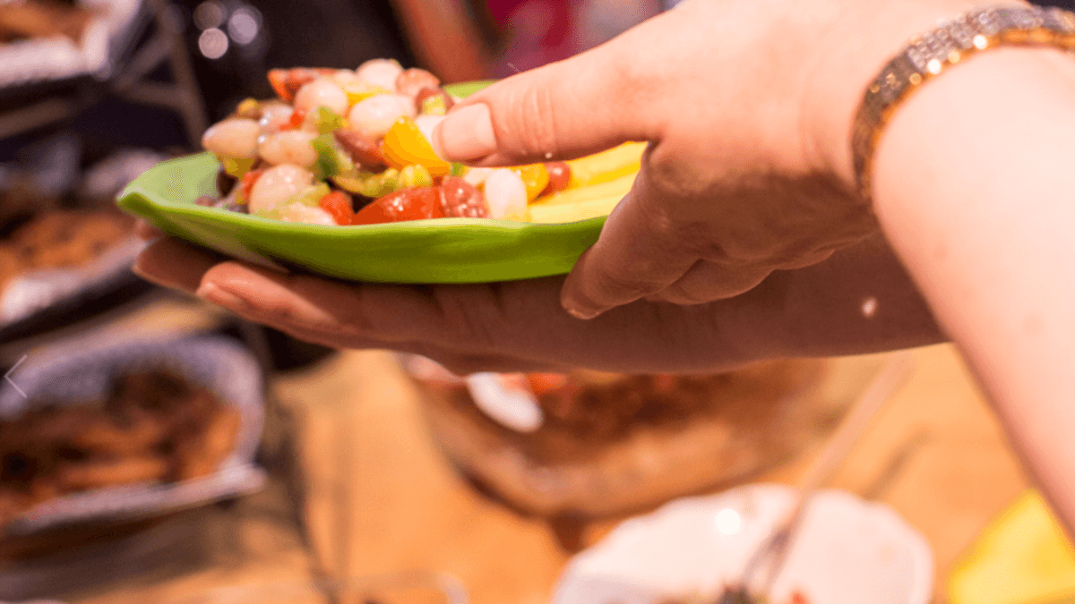 Plato de ensalada con alubias y mango, sostenido por una mujer.