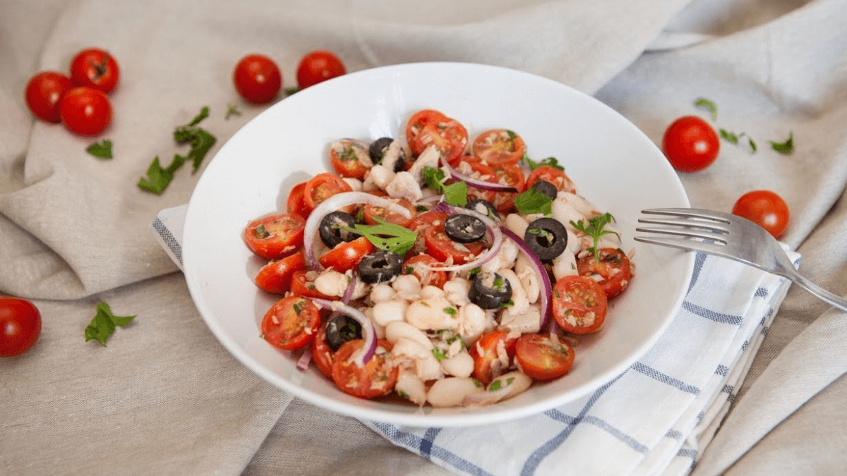 Ensalada de alubias blancas y tomates en un plato hondo.